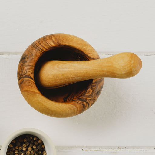 Wooden Pestle & Mortar Set shown from above and empty next to small bowl of peppercorns